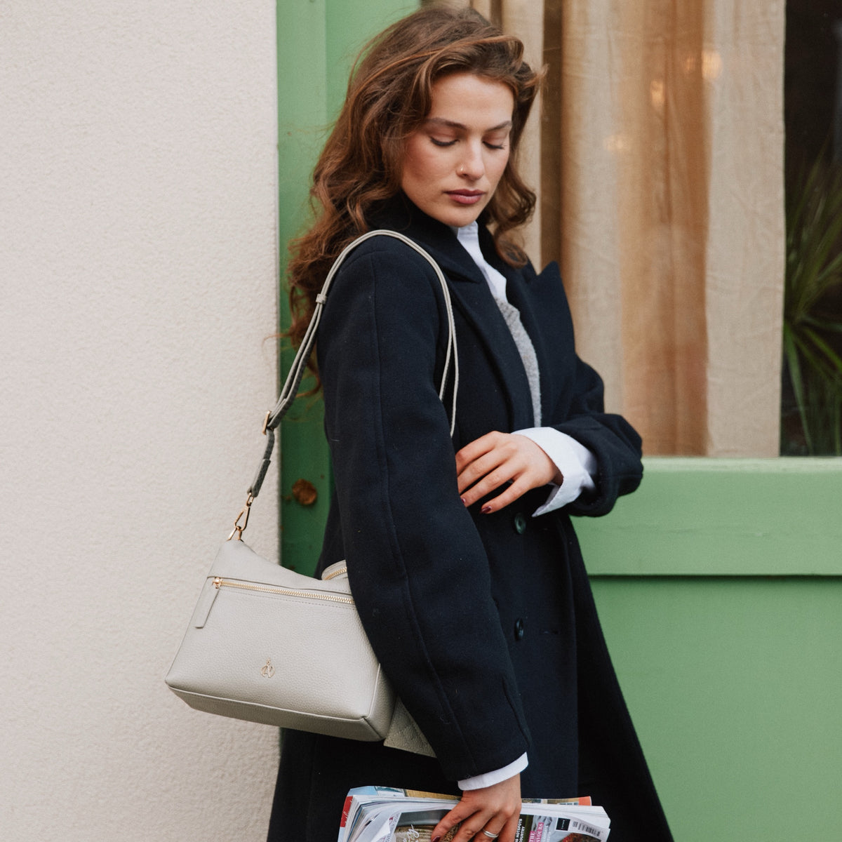 Model carrying the Fiona Fog Grey bag on the shoulder by a green door